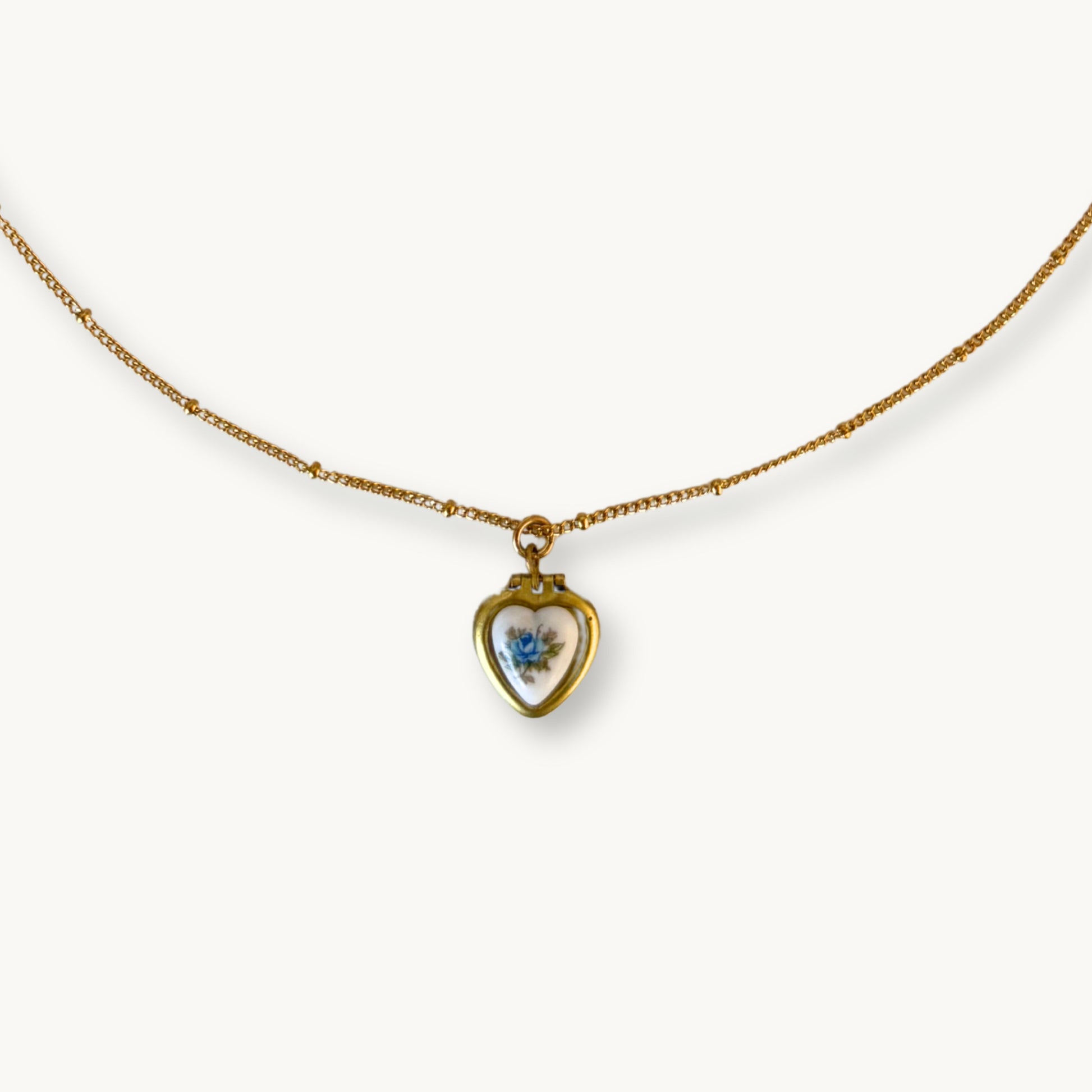 Close-up of the Blanche Necklace showing the ceramic blue rose and patina brass locket.