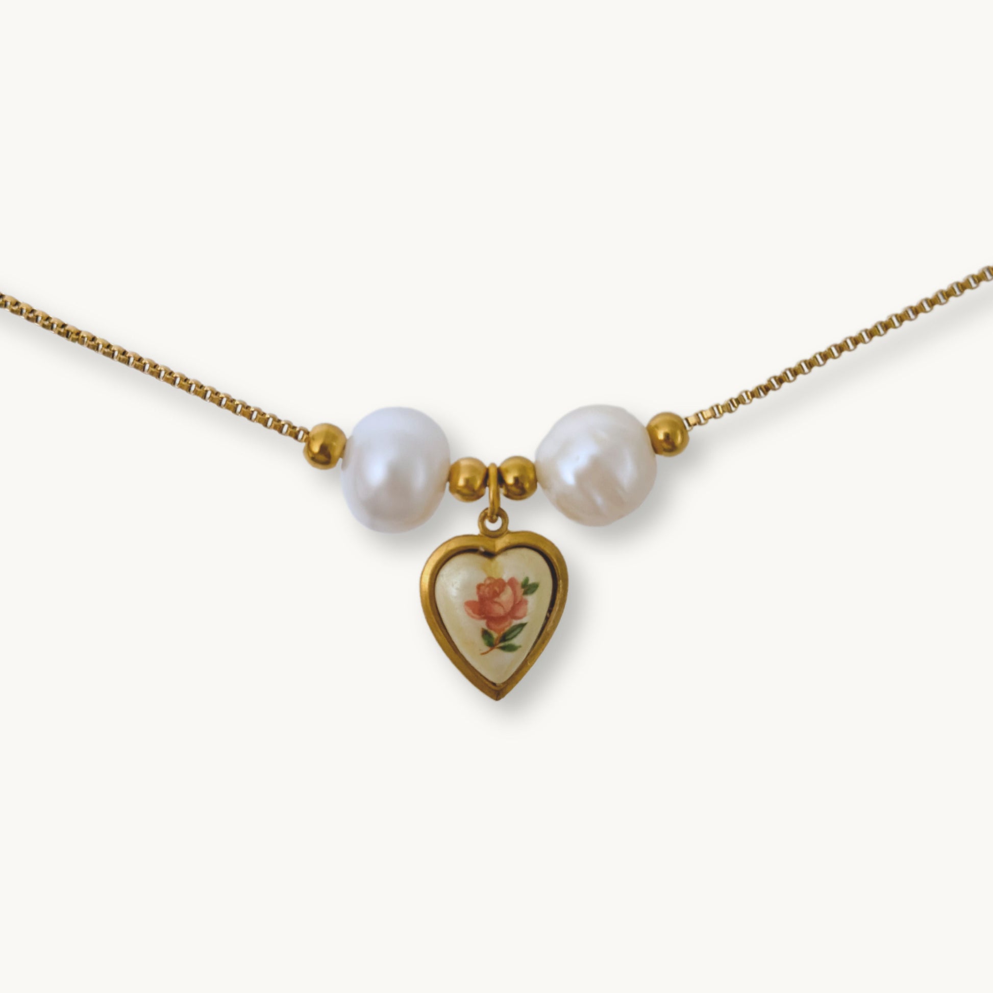 Close-up of Monica Necklace featuring lustrous baroque pearls and a vintage-inspired rose heart pendant on a gold-plated chain.