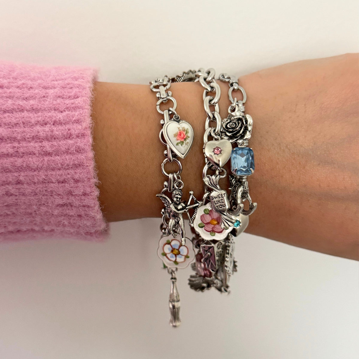 Gold and silver charm bracelets stacked for a layered look.