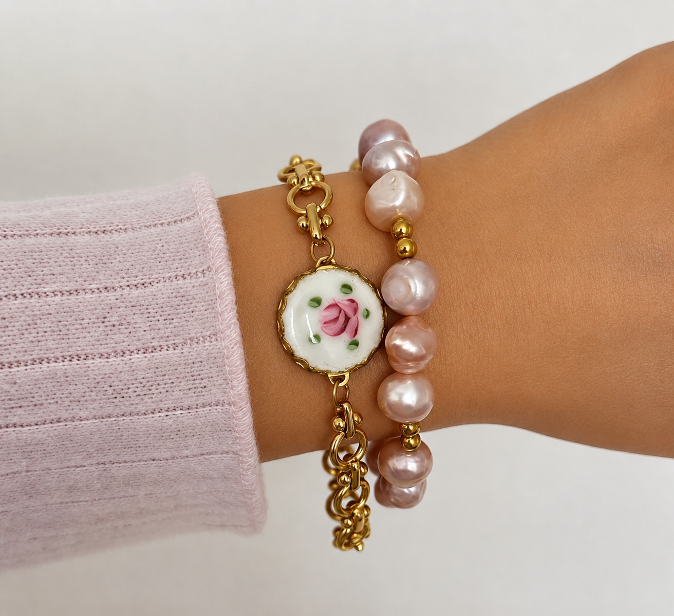 Gold and silver charm bracelets stacked for a layered look.