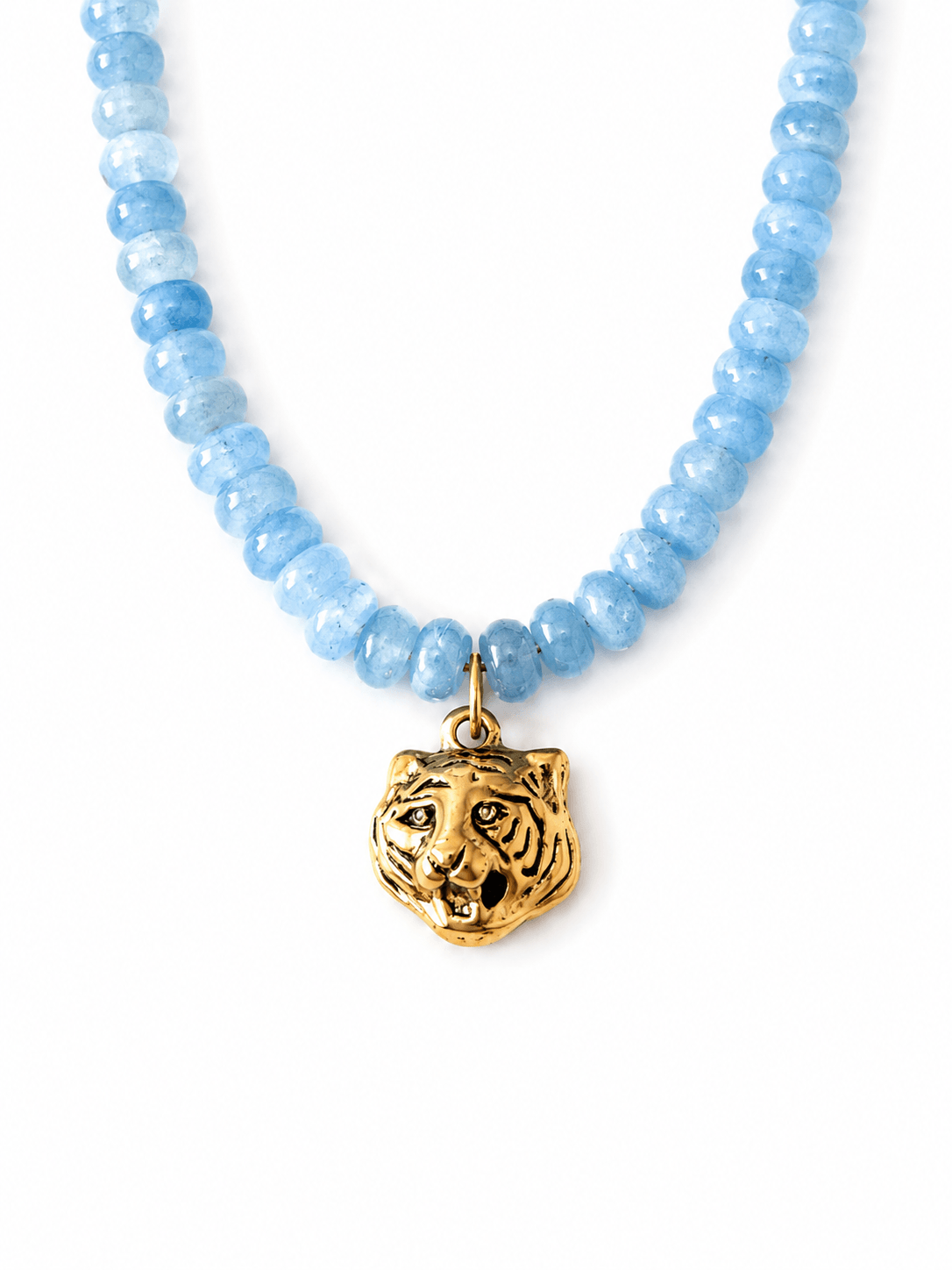 A beaded necklace featuring light blue faceted gemstone beads and a textured gold tiger head pendant, displayed on a clean white background.