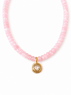 A delicate necklace made of small faceted pink beads with a gold-toned pendant featuring a heart-shaped clear stone, shown on a plain white background.