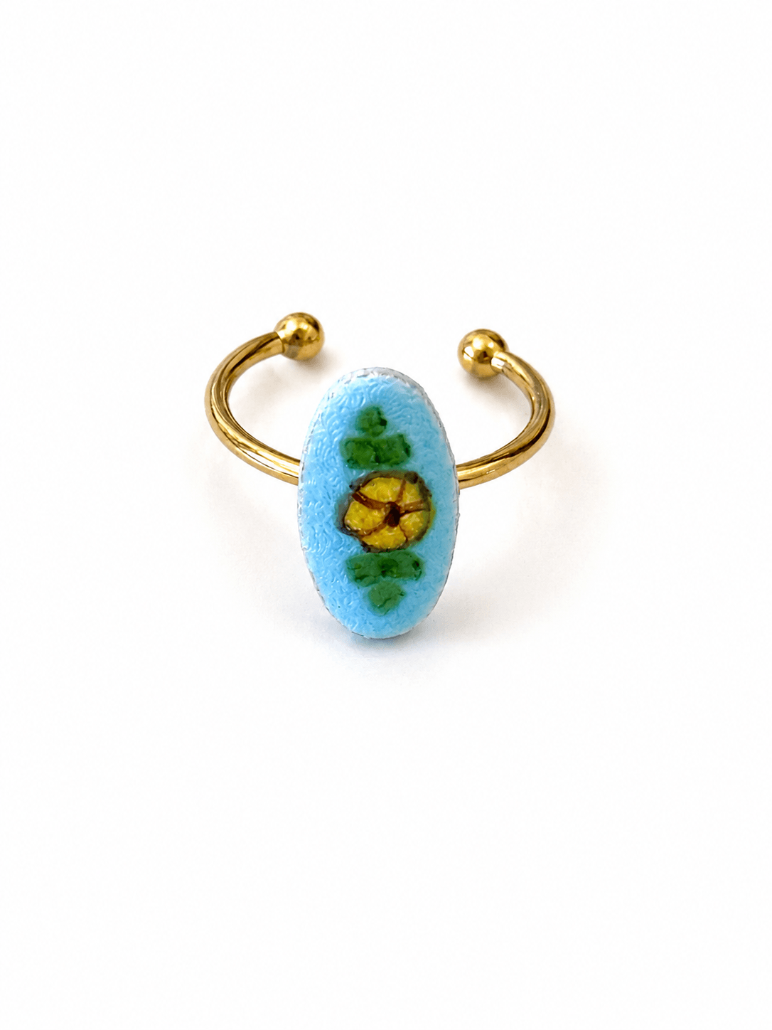 A gold-plated open cuff ring featuring a light blue oval bezel set with a yellow flower and green leaves, shown on a plain white background.