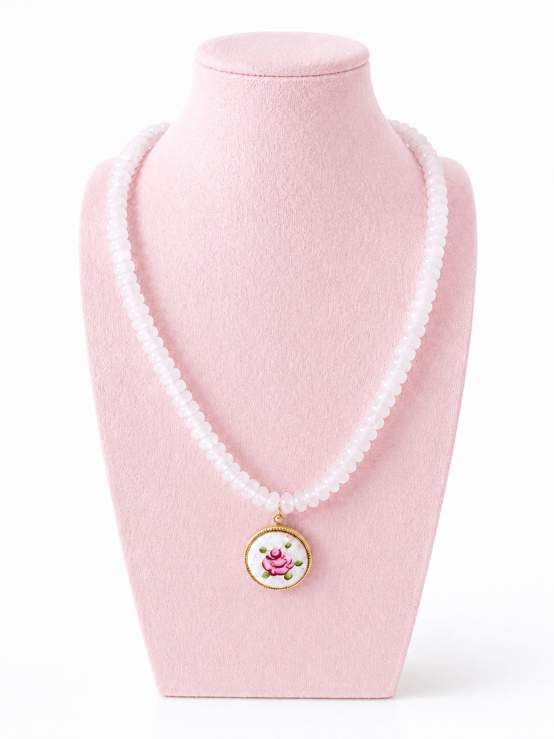 A white beaded necklace with a round pendant featuring a pink cartoon character on a white background with a gold border, displayed on a light pink jewelry bust against a white background.