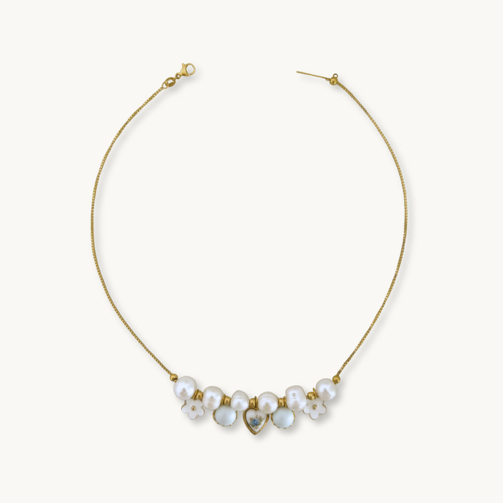 Freya Necklace - 18K gold-plated box chain with baroque pearls, a white flower, a pastel blue glass pearl in a lace setting, and a blue rose heart charm on brass, 17 inches in length.