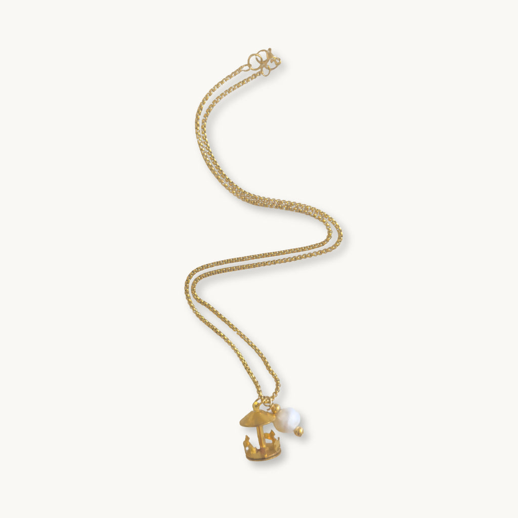 Gertrude Necklace - 18K gold-plated cross chain with a brass spinning merry-go-round charm and a handmade freshwater pearl accent, 17 inches in length.