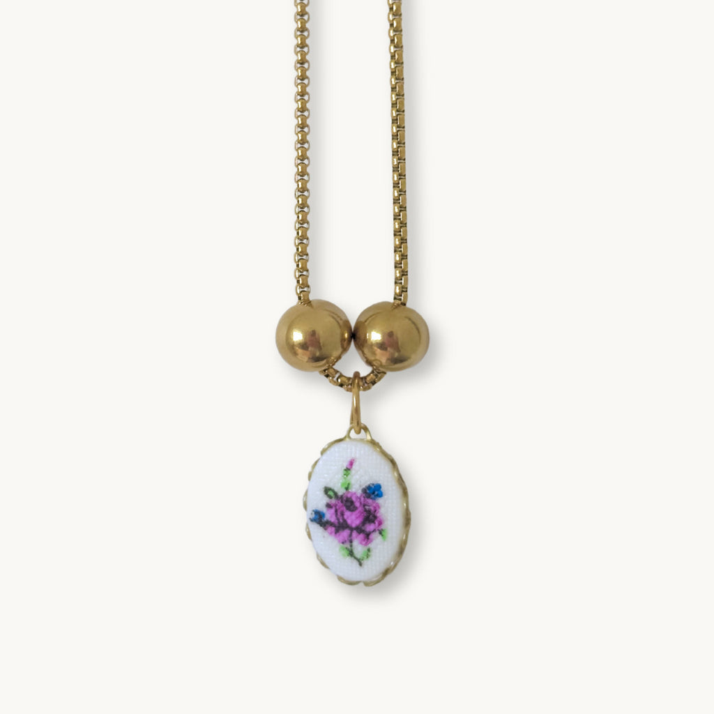 Close-up of the Hilda Necklace showcasing its intricate floral needlework design and elegant gold-plated details.