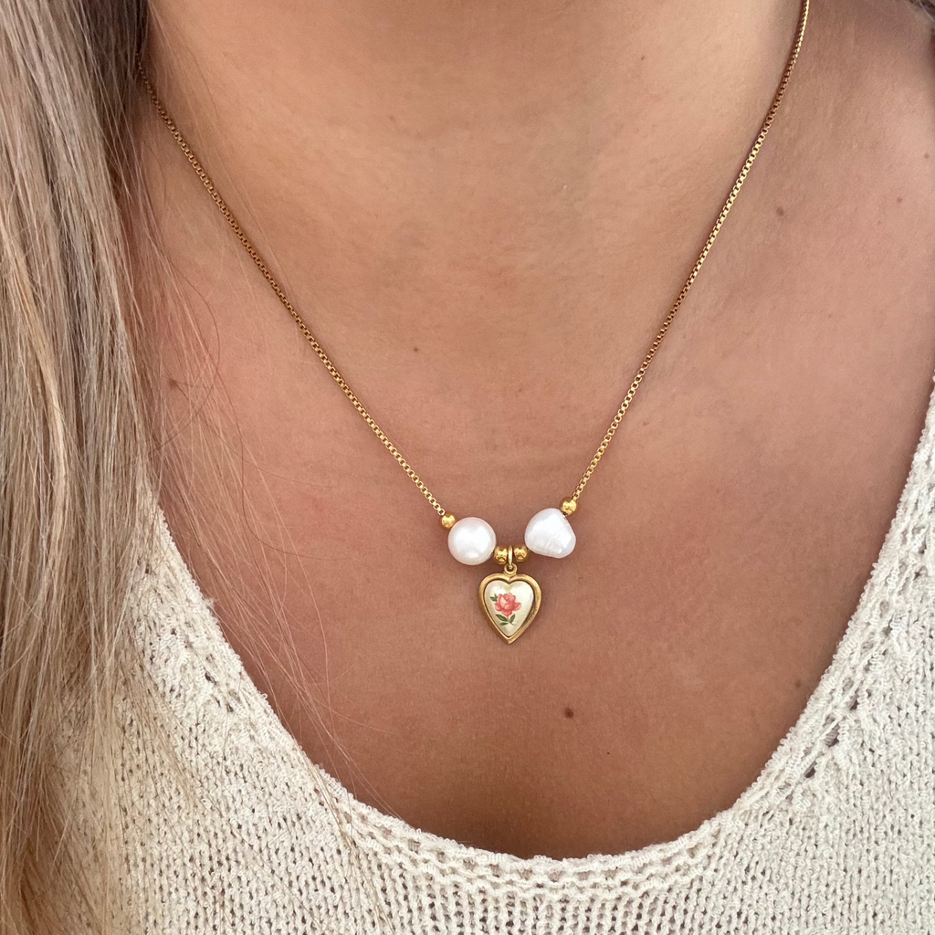 Model wearing The Monica Necklace featuring an 18K PVD gold plated snake chain with baroque natural pearls and an elegant English rose heart pendant set on brass. 17 inches in length.
