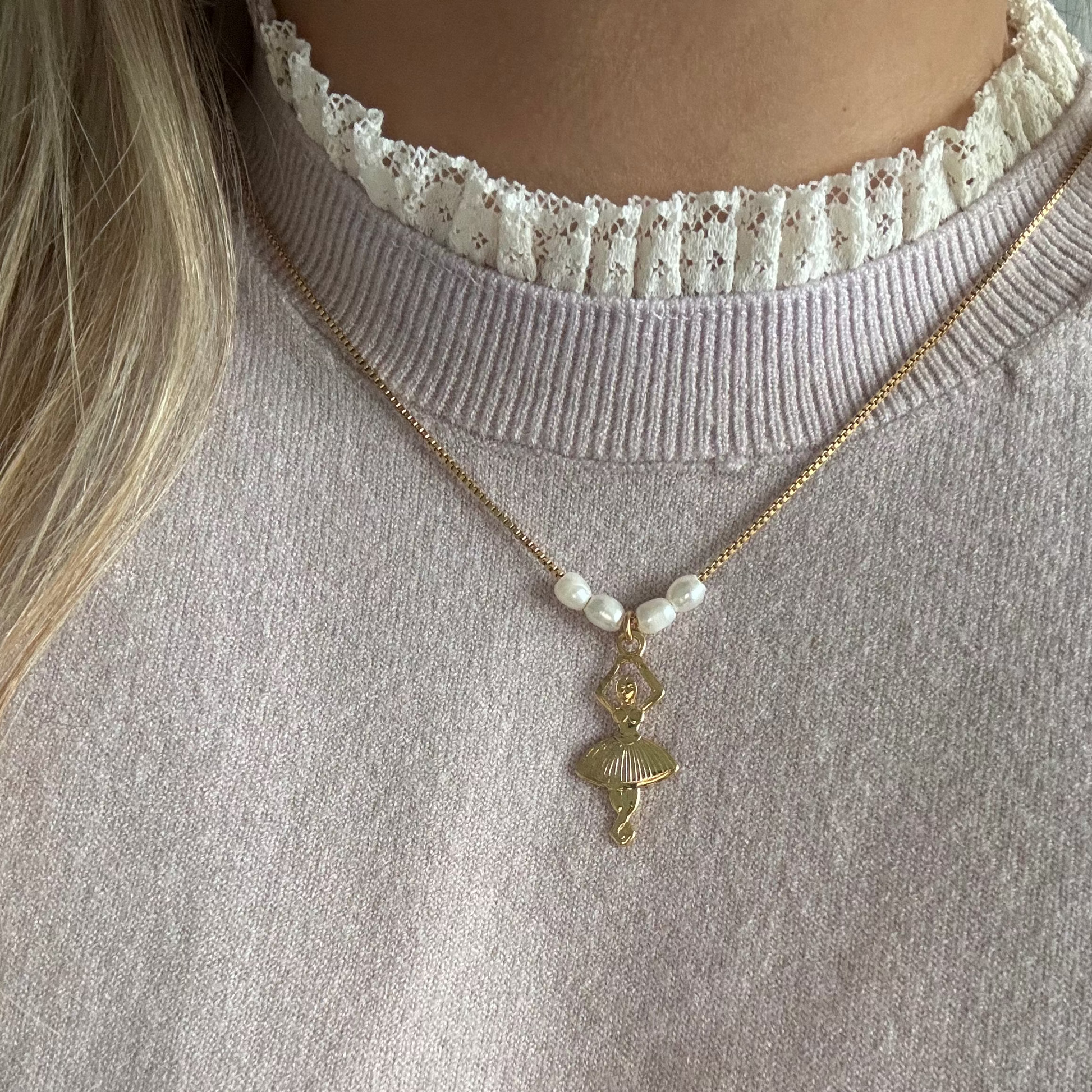 Model wearing the Ballerina Necklace — a dainty snake chain adorned with rice freshwater pearls and a graceful gold ballerina pendant, styled for an elegant and dreamy look.