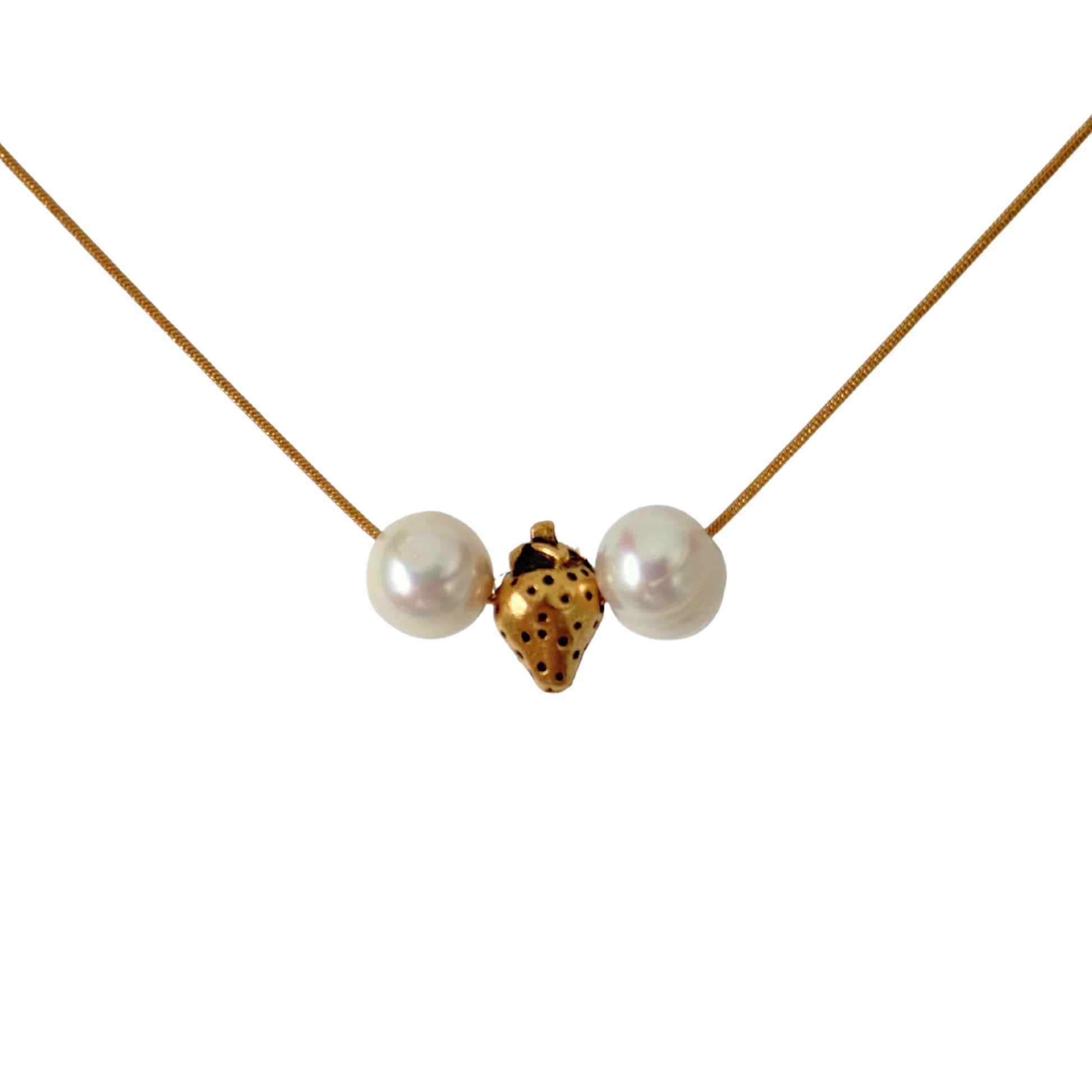 Close-up of gold strawberry charm and pearls