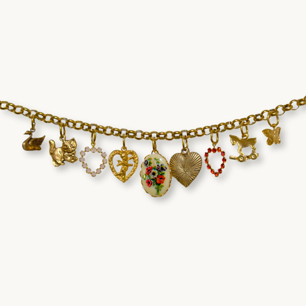 Close-up of the Maya Necklace featuring a heart Swarovski, swan, and horsey pull toy charm.