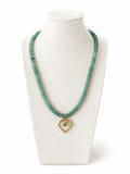 A beaded necklace in a translucent light green tone with a small gold heart-shaped pendant, displayed on a white jewelry bust against a white background.