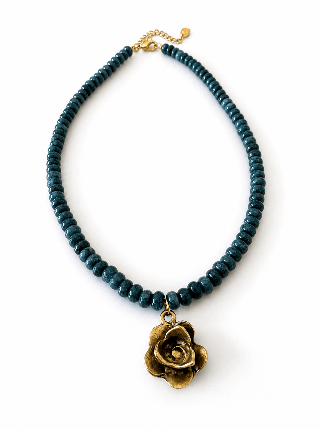 A dark teal beaded necklace with a bronze rose flower pendant, displayed on a clean white background.