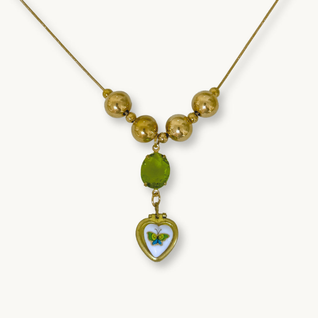 Close-up of the Miel Necklace featuring a gold snake chain, lime green stone drop, and vintage locket.