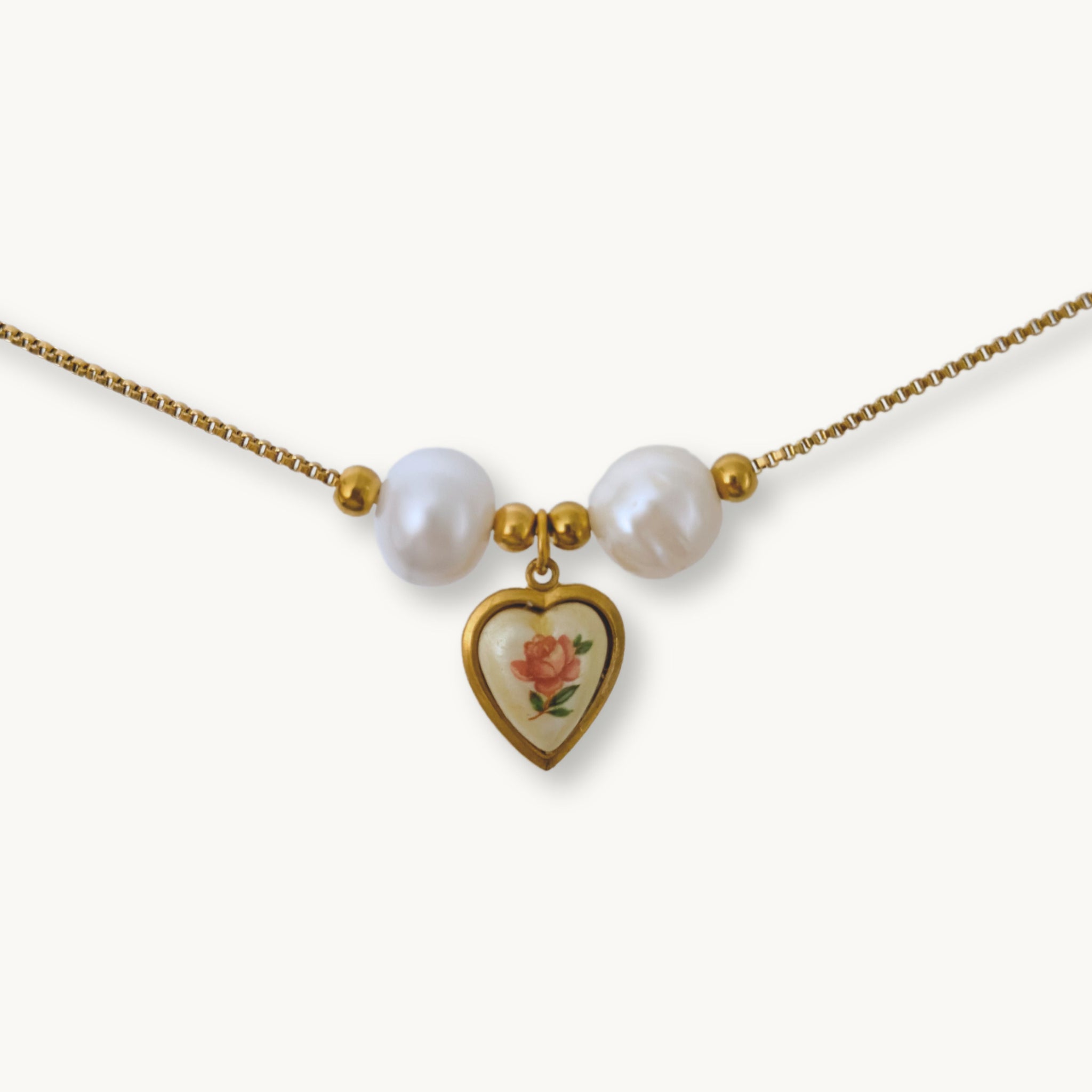 Close-up of Monica Necklace featuring lustrous baroque pearls and a vintage-inspired rose heart pendant on a gold-plated chain.