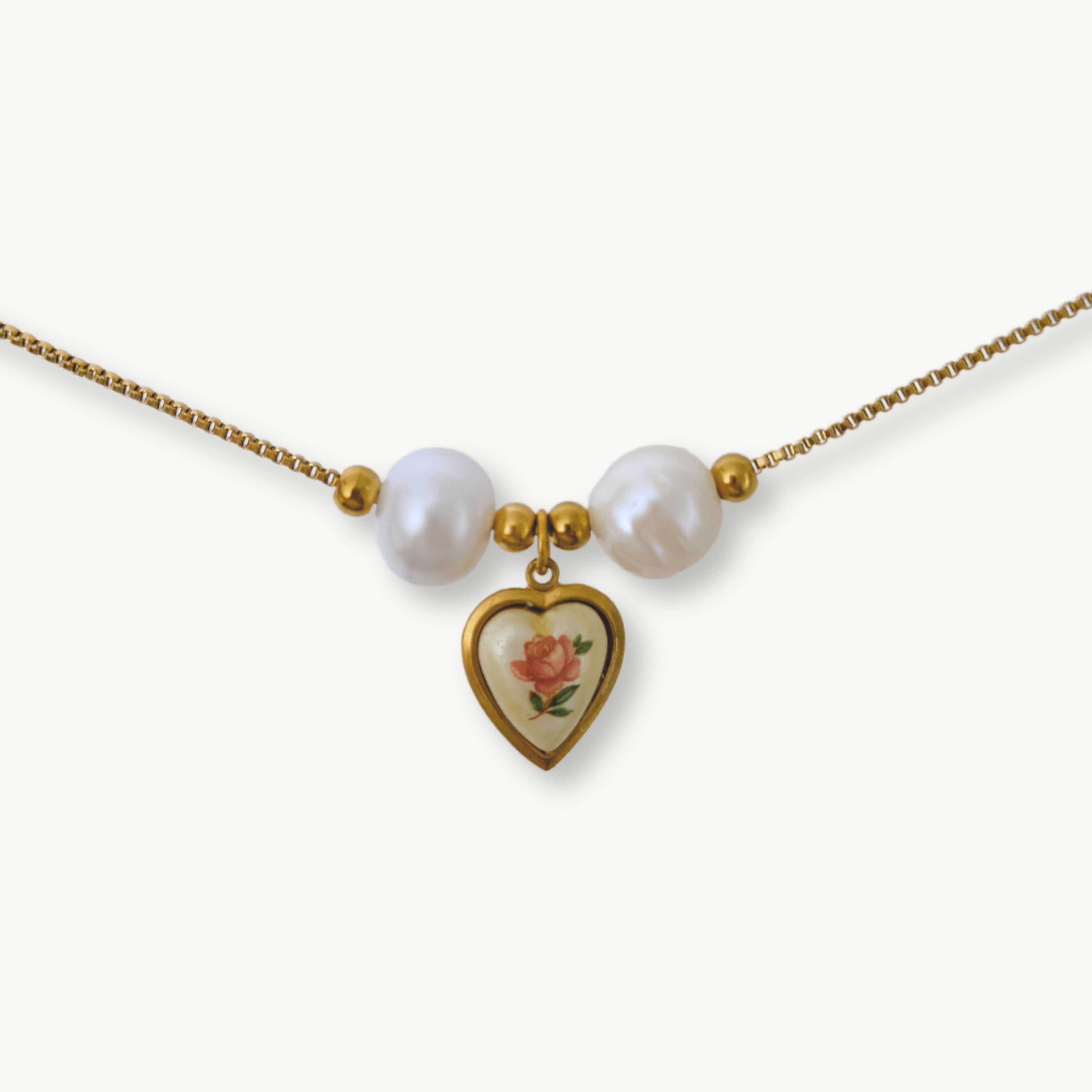 Close-up of Monica Necklace featuring lustrous baroque pearls and a vintage-inspired rose heart pendant on a gold-plated chain.