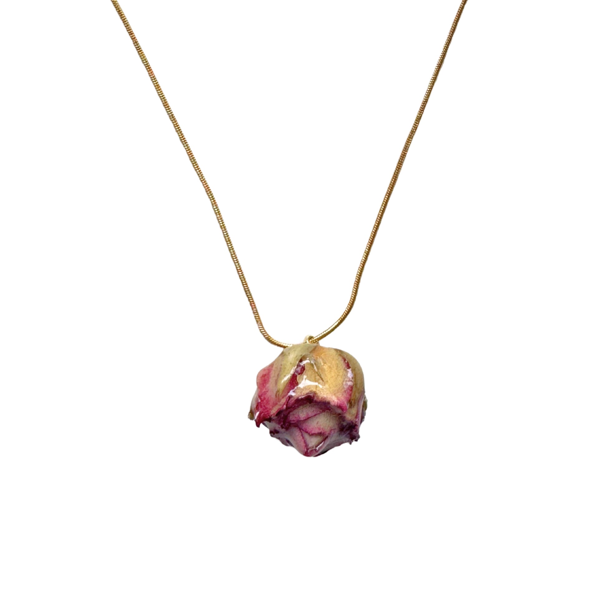 Close-up of preserved rose charm on gold snake chain