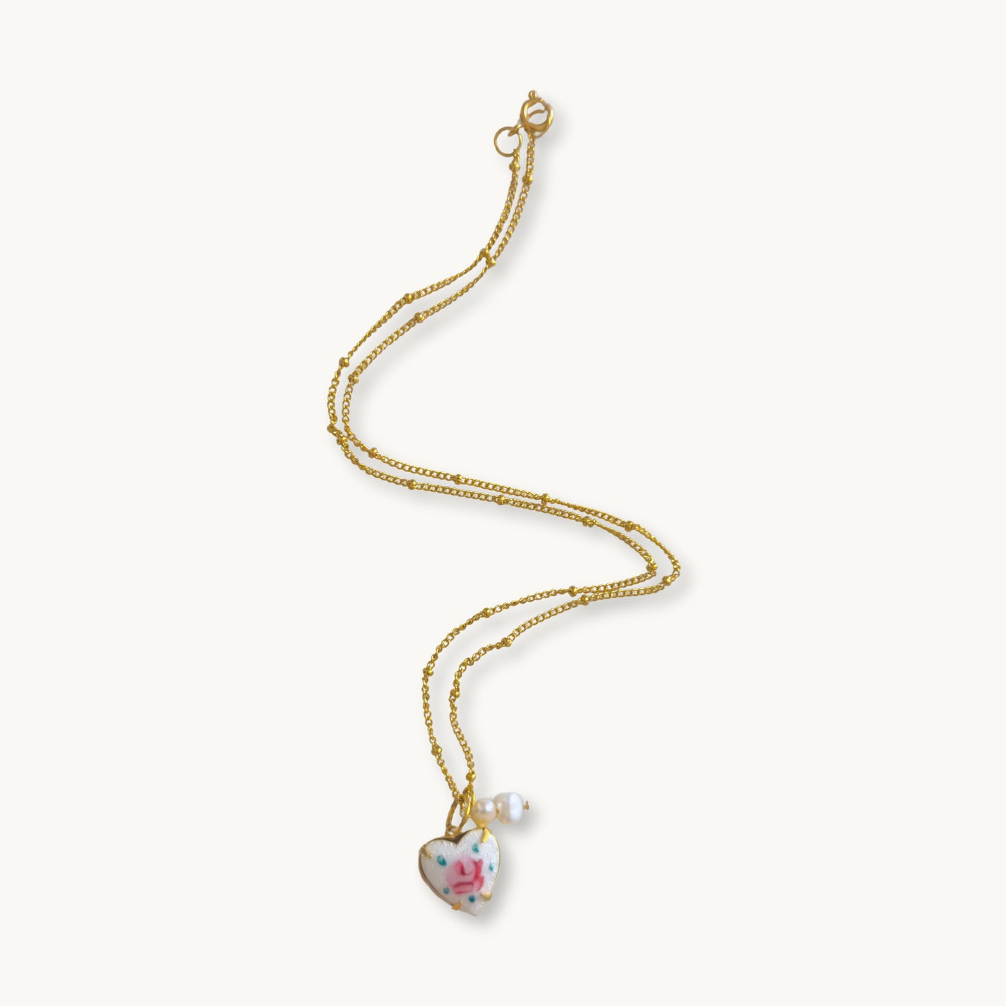 Rosina Necklace featuring a gold-plated beaded Figaro chain with a heart-shaped guilloche rose pendant.