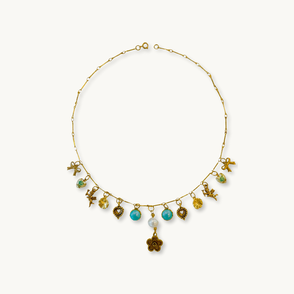 Sabrina Necklace featuring a gold-plated barlink chain with intricate charms and a pearl drop pendant.