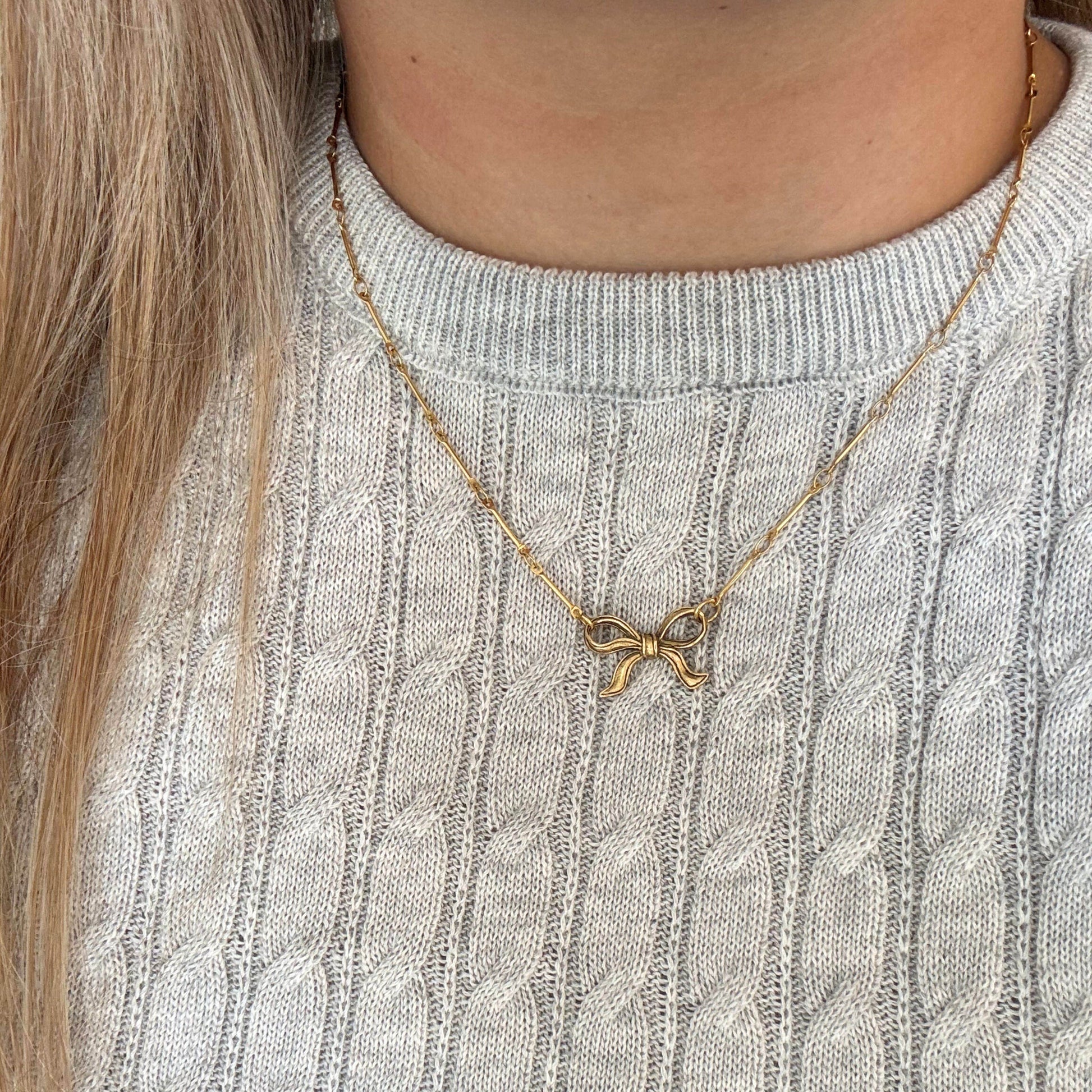 Model wearing the Tullah Necklace with dainty gold bar links and a delicate bow charm at the center