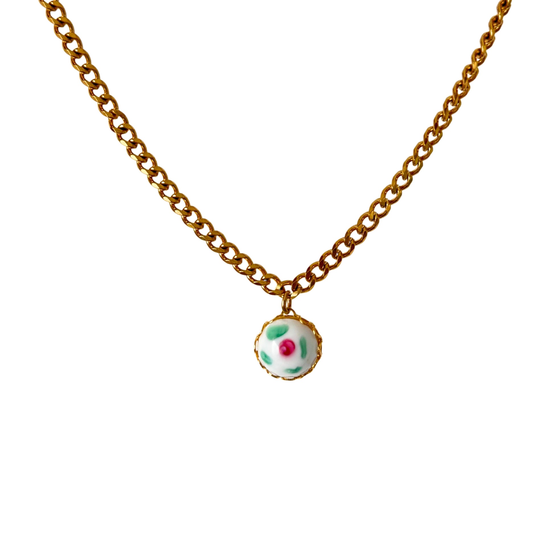 Close-up of hand-painted milky ceramic pendant on Cuban chain